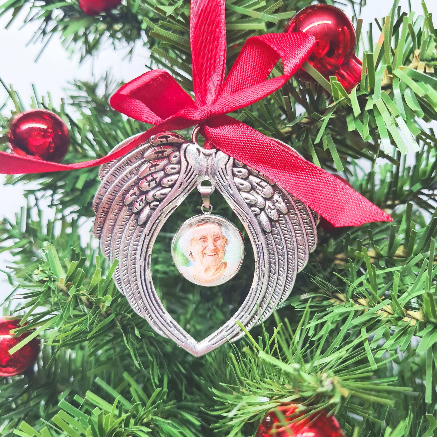 Christmas ornament with angel wings and a personalised photo set in a silver pendant with glass in a Christmas tree