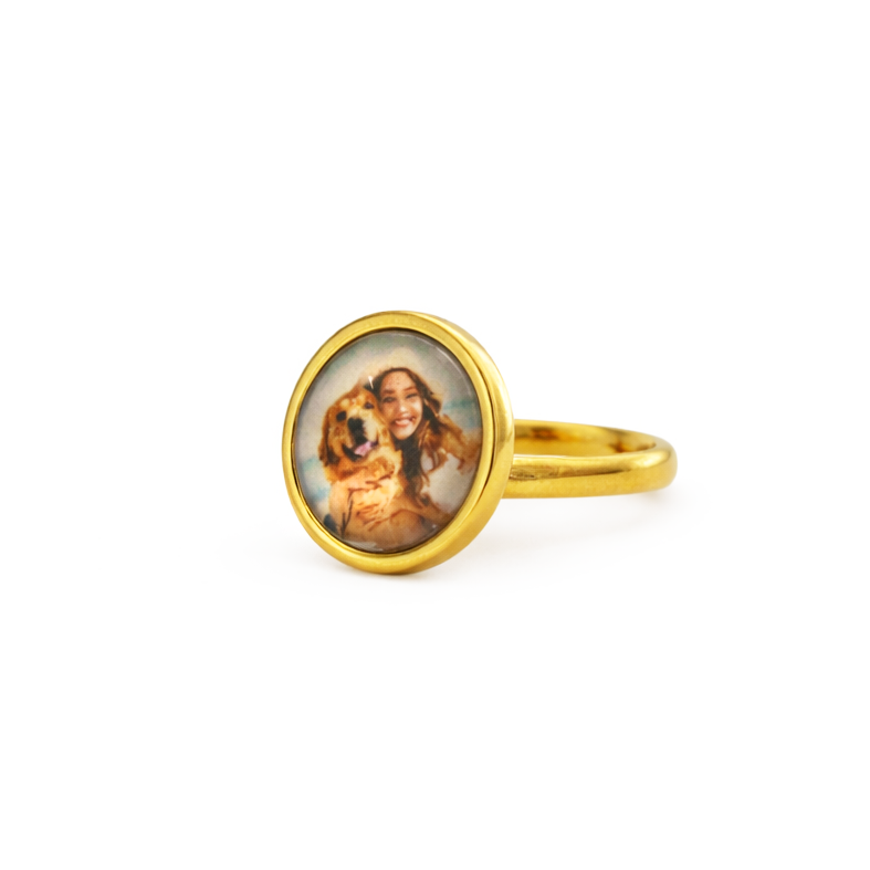 Gold ring with a circular pendant featuring a portrait on a white background
