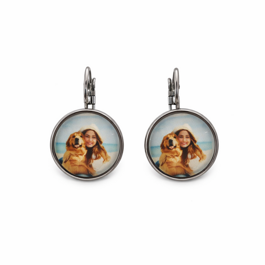 Pair of earrings with circular images of a person and a dog on a white background