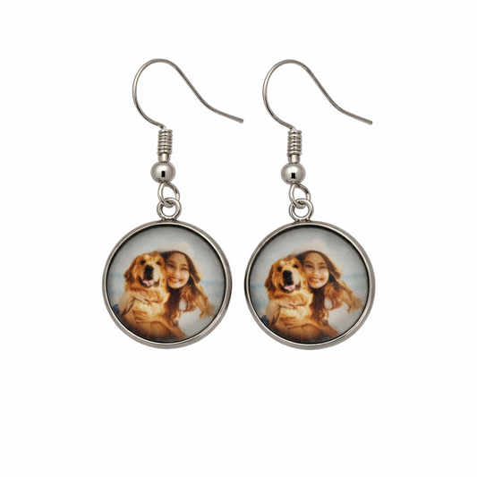 Pair of earrings with circular charms featuring a person and a dog on a white background