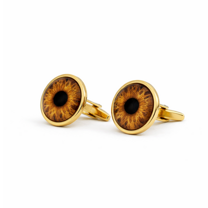 Gold cufflinks with eye design on a white background